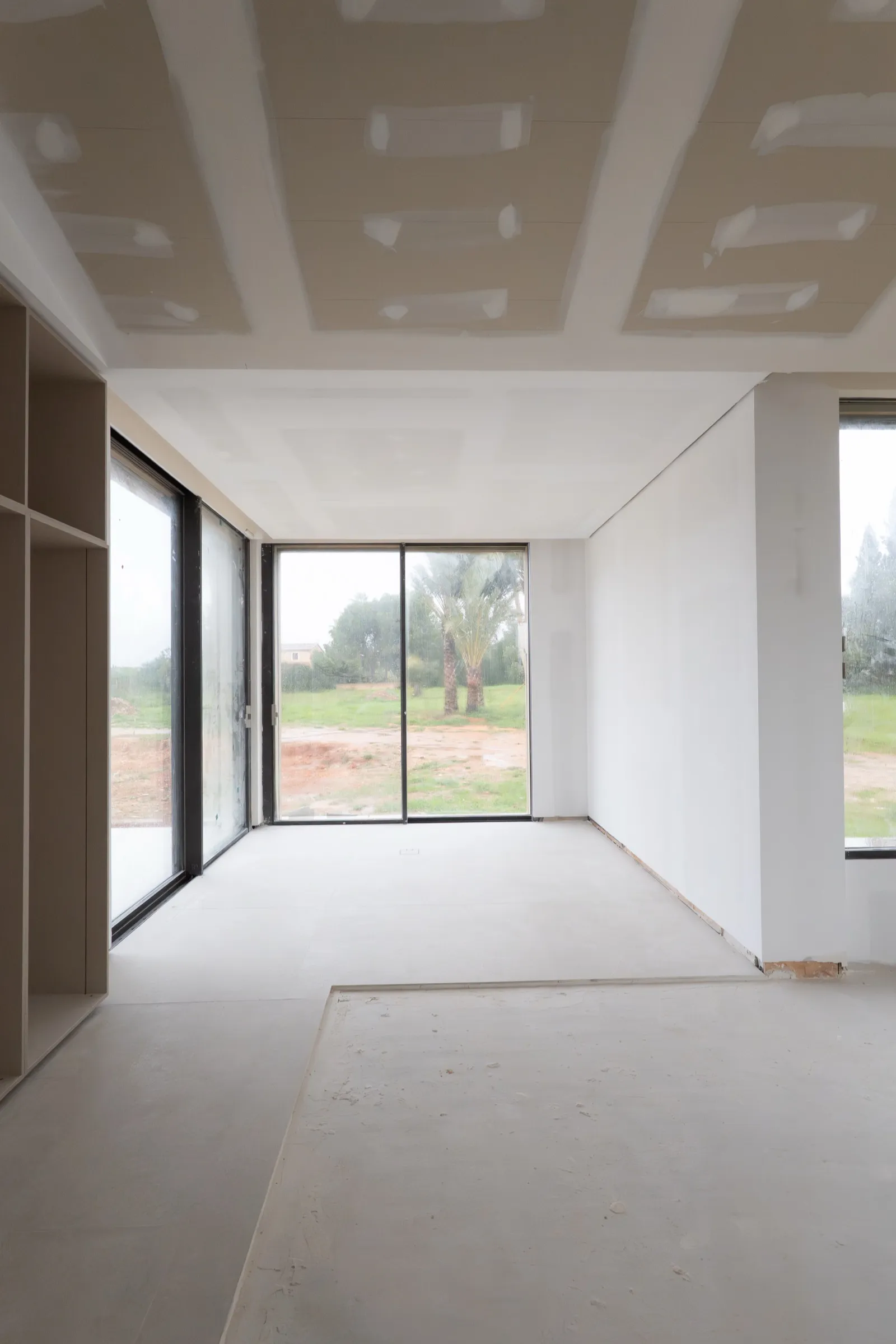 Salón de villa con falso techo de pladur y grandes ventanales al jardín en Mallorca